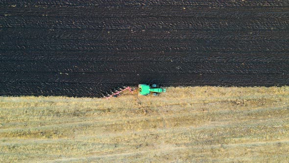 Aerial view of a tractor plowing agricultural farm field.