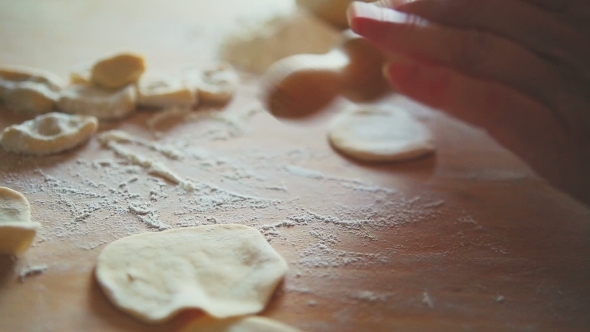 Making Of Dumplings. A Woman Is Rolling Dough With A Rolling Pin On A Table 