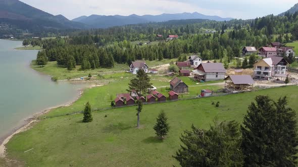 Aerial Take off Shot of Lake Edge with ever green trees and building site