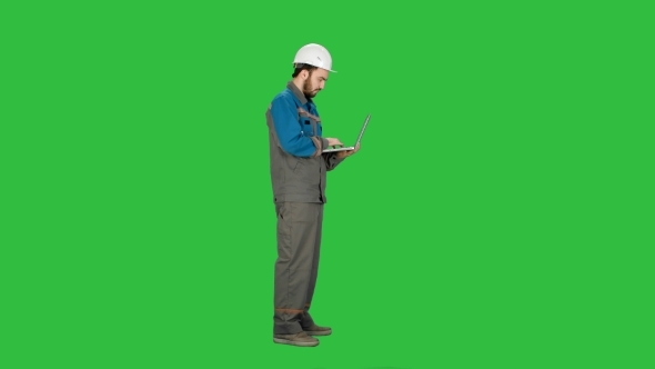 Attractive Engineer Using Laptop On a Green Screen, Chroma Key.
