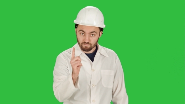 Man In The Construction Helmet With a Raised Finger On a Green Screen, Chroma Key.