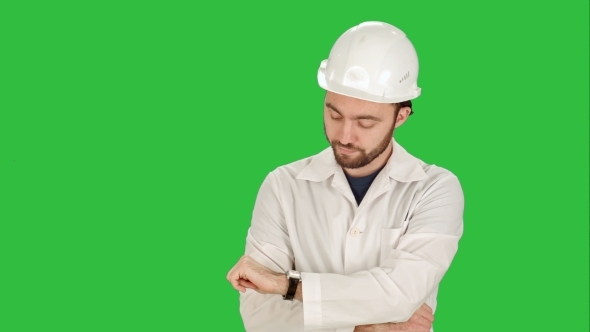Construction Worker Looking At His Watch. Builder Waiting For a Meeting On a Green Screen, Chroma