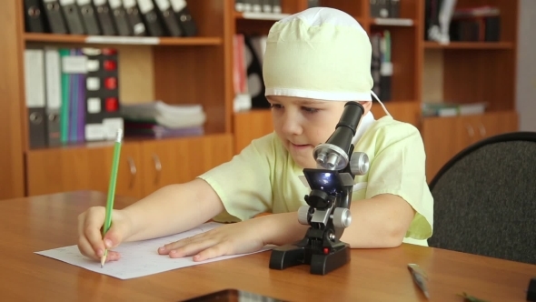 A Little Boy With a Microscope In a Research Lab