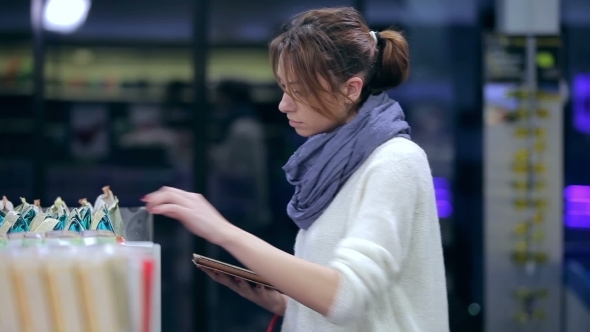 Pretty Girl Browses Shopping List On The Tablet alt