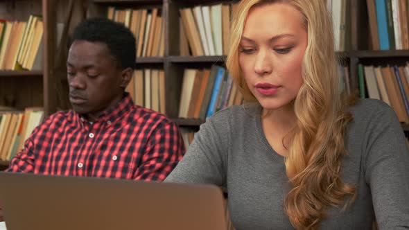 White Girl and Black Guy Surrounded By Books in Library