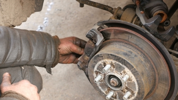 Auto Mechanic Working On Brakes In Car Repair Shop