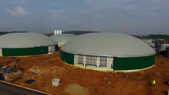 Building of bio gaz station in green field. Gray roofs and green walls of round metal construction.