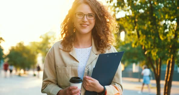 Successful lady freelancer or modern office worker manager walks with coffee cup and documents