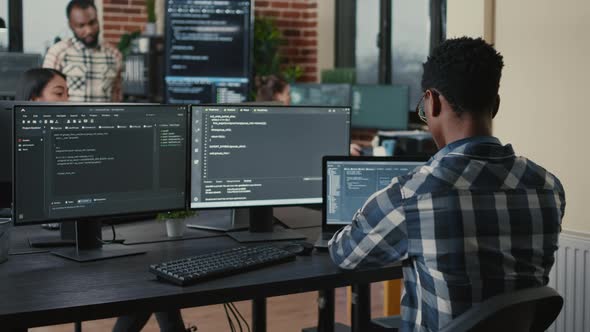 Software Developer Writing Code on Laptop and Computer Keyboard Looking at Multiple Screens