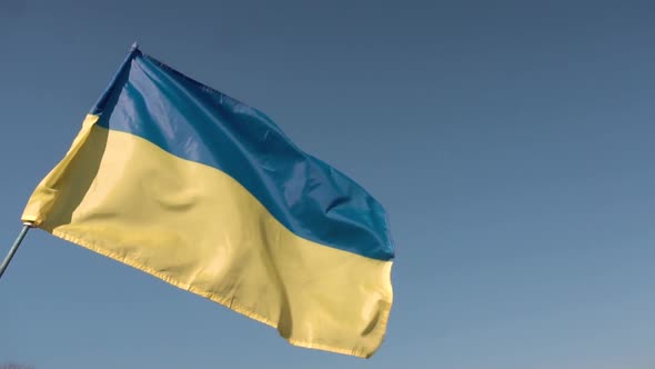 Ukrainian flag on a flagpole. blue sky background.