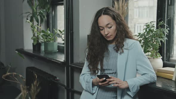 Young Attractive Woman with Smartphone at Workplace