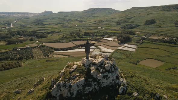 Statue of the Risen Christ in Gozo, Malta shown in a 180 degrees circling drone shot with the green
