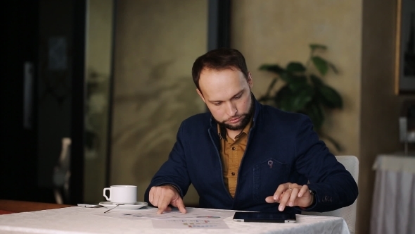 Businessman With Tablet Computer Calculating Data On Smartphone In Cafe