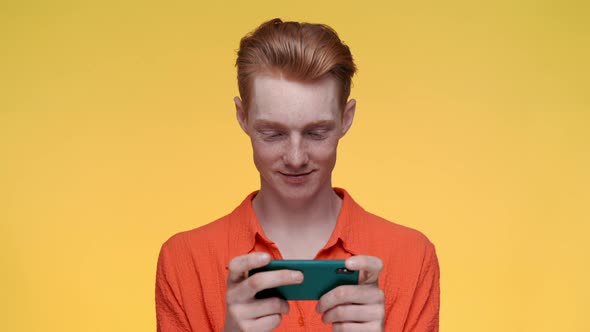 Smiling Redhead Man Playing Games on Smartphone