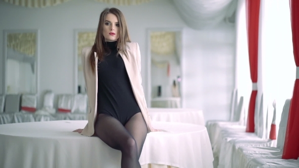 Lady Posing For The Camera While Sitting On a Table In The Banquet Hall