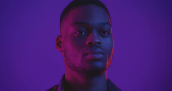 Studio Portrait of Handsome African American Guy in Neon Lights, Looking Away, Close Up