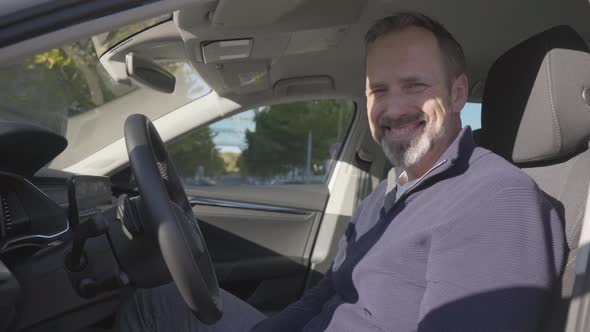 A Middleaged Handsome Caucasian Man Smiles at the Camera in His Car  Closeup