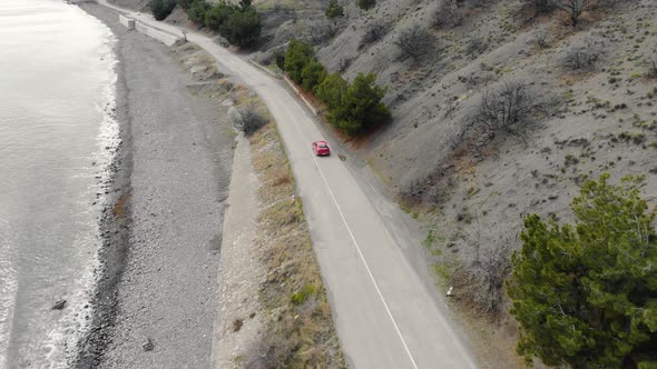 Aerial View of Red Car Moving Along Road Near Sea