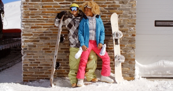 Close Couple Posing With Snowboards Against Garage