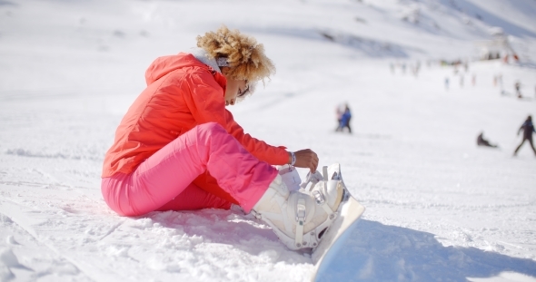 Skier Putting On Her Snowboard alt