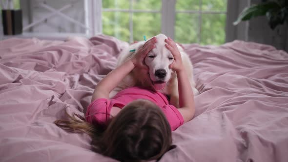 Little Girl Stroking Her Puppy in Bedroom