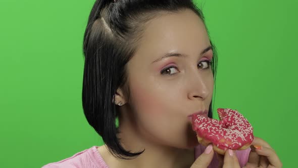 Beautiful Young Woman with Great Pleasure Eats a Donut. Chroma Key