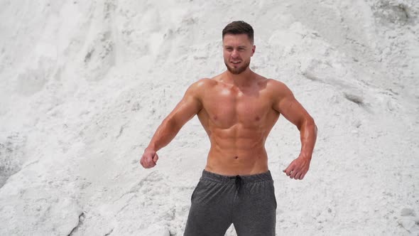 Spots man standing in pose. Well built bodybuilder posing in the mountains