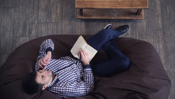 Attractive Man Talking On The Phone While Lying In a Chair.