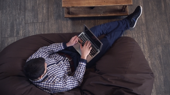 Attractive Man Lying In a Chair And Buying Online With a Credit Card.