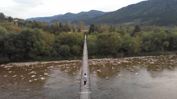 Aerial View of Tourist Woman Walk on Wooden Bridge Across Mountain River