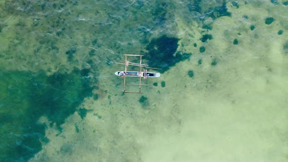 Aerial top down drone shot of a phishing boat on clear water in Zanzibar, Tanzania. Medium shot.