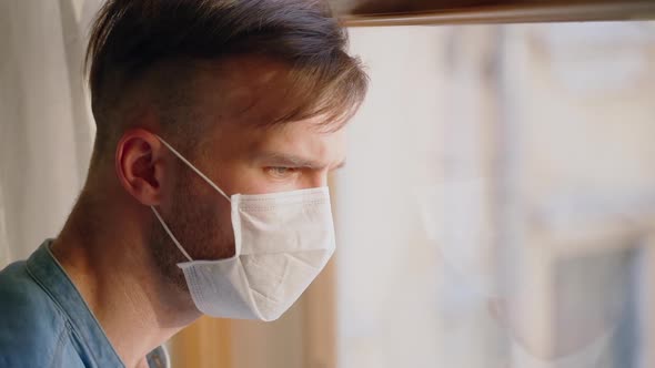 Sad Serious Man in Self Isolation Wearing Face Mask Looking at the Window