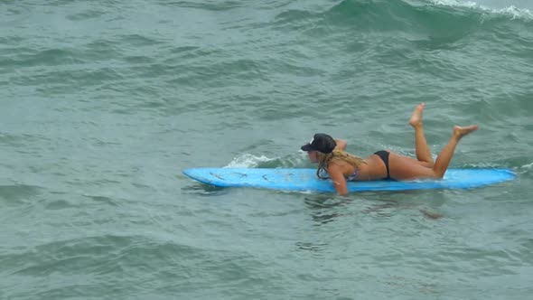 A young woman surfing in a bikini on a longboard surfboard.