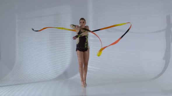 Gymnast Whirl with Ribbon and Stand on the Leg. White Background