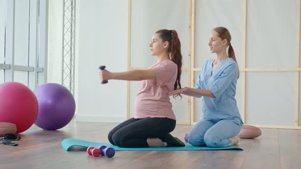 A Young Pregnant Woman is Doing Exercises with a Health Worker in a Clinic