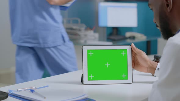African American Man Doctor Analyzing Sickness Diagnosic Report Holding Mock Up Green Screen Tablet