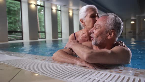 Loving Aging Couple Relaxing in Pool of Spa Hotel