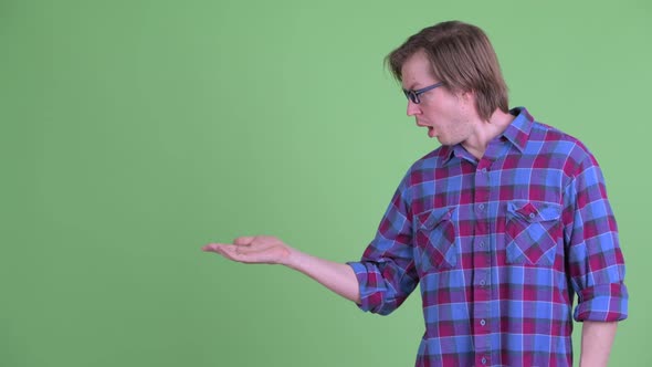 Young Handsome Hipster Man Showing Something and Looking Shocked