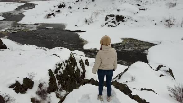 Video From the Back of a Girl in a Beige Jacket Stands on Top of a Slope