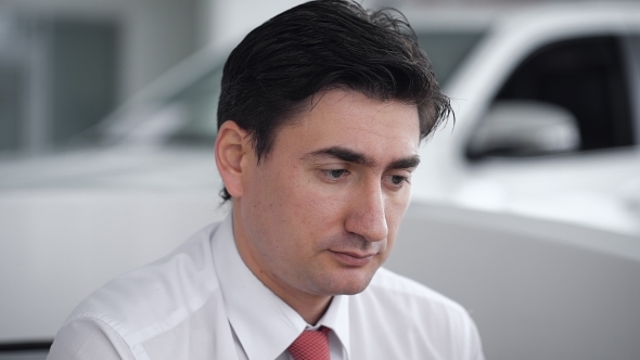 Car Salesman Sitting In Showroom