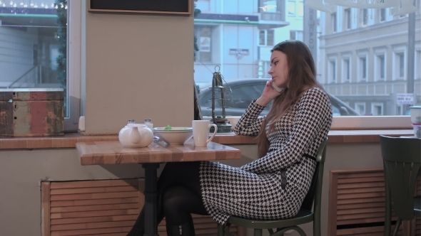 Serious Business Woman Talking On The Mobile Cell Phone Sitting In a Coffee Shop Or Tea-room