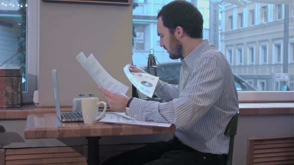 Businessman In a Cafe Reading With Interest a Contract Document. 