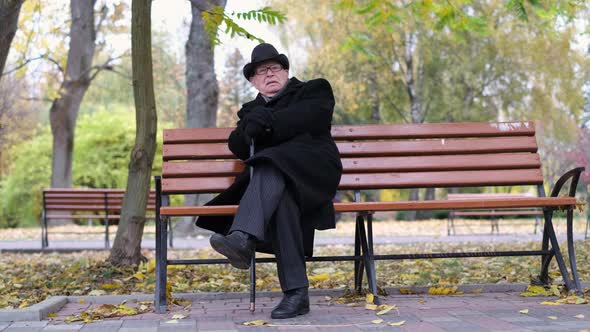 A Lonely Old Man is Sitting on a Park Bench