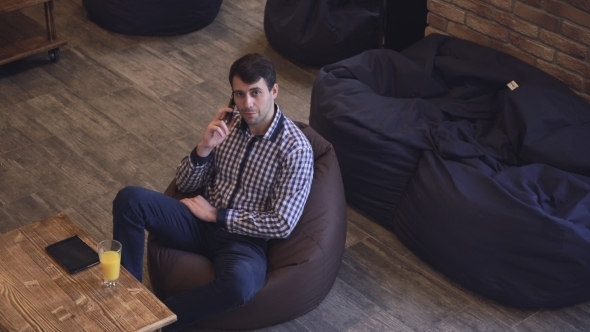 Middle-aged Man Sitting In a Chair Bag, Holding The Phone Near The Ear