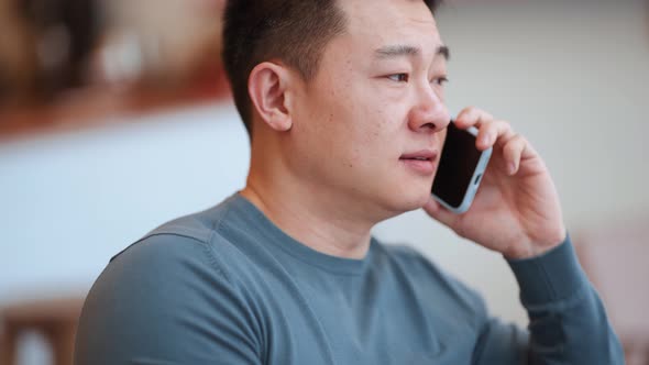 Cheerful Asian young man talking by phone