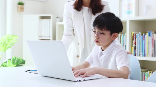 Smart young student receiving online learning instruction on laptop from mom and teacher