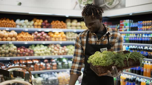 African American Smiling Worker Arranging Greens in the Supermarket