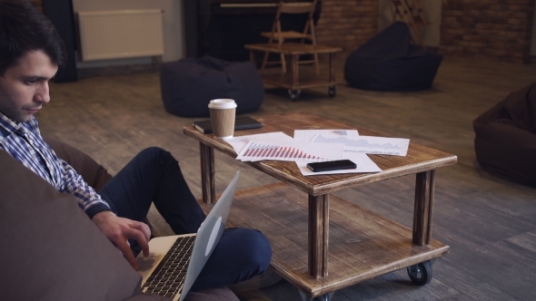 The Man Sitting Resting, Looking At The Monitor And Drinking Coffee. alt