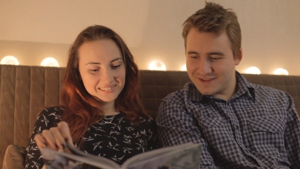 Young Couple Looking Magazine Or a Book At Home