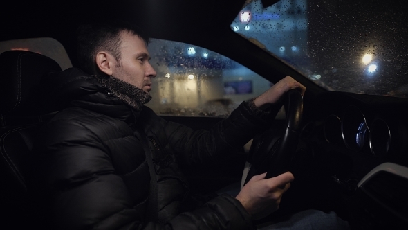 Man Driving His Modern Car at Night in a City
